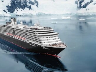 Large cruise ship sailing through icy Arctic waters with snow-covered cliffs in the background.