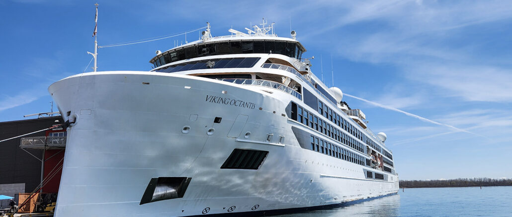 Large white cruise ship named Viking Octantis docked at a marina on a sunny day.