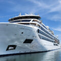Large white cruise ship named Viking Octantis docked at a marina on a sunny day.