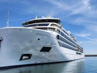 Large white cruise ship named Viking Octantis docked at a marina on a sunny day.