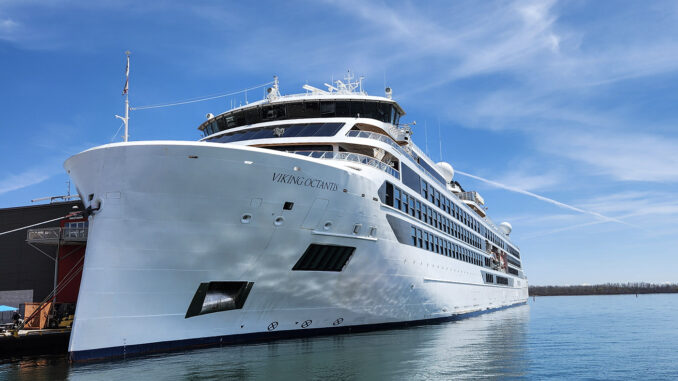 Large white cruise ship named Viking Octantis docked at a marina on a sunny day.