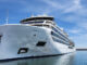 Large white cruise ship named Viking Octantis docked at a marina on a sunny day.