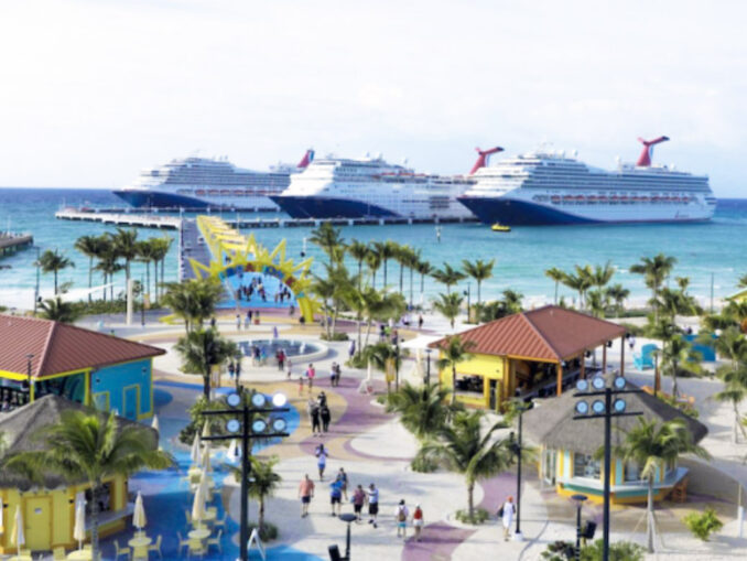 Two large cruise ships docked offshore as a sunny tropical port comes to life with palm trees and colorful buildings along a promenade.